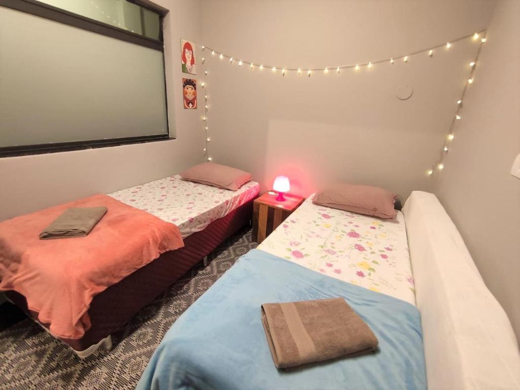 2 camas en una habitación con luces en la pared en Hospedaria Studio 373 - Vila Mariana - Valores Acessíveis, en São Paulo