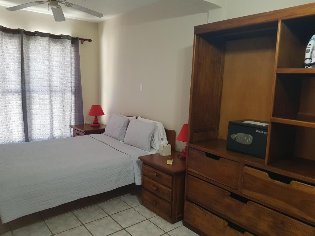 1 dormitorio con 1 cama y vestidor con TV en Wild Orchid, en Placencia Village