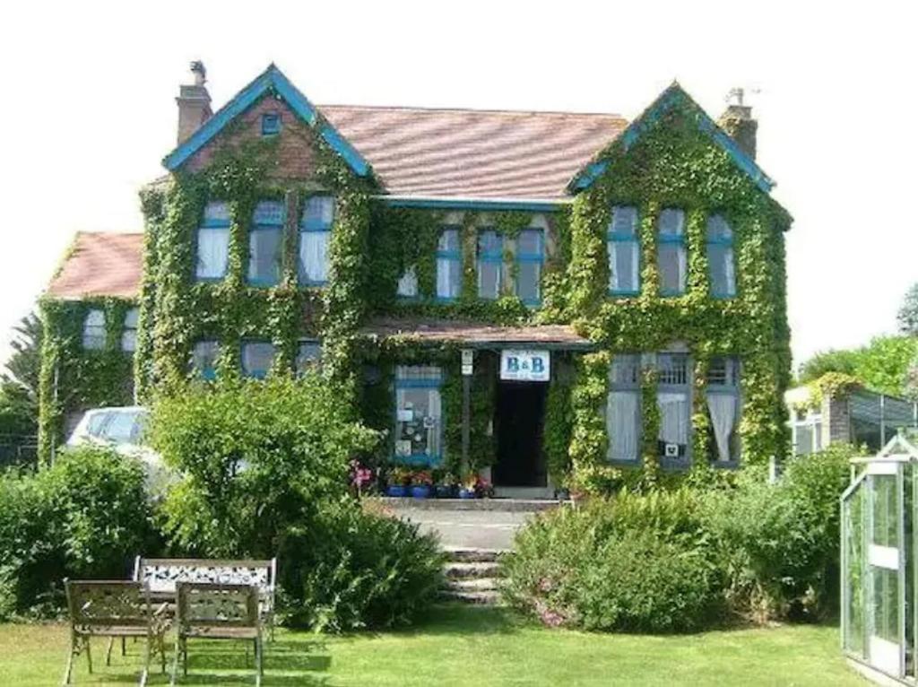 a house covered in ivy with a bench in front of it at Penkerris in St. Agnes