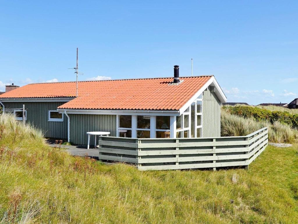 a small house with an orange roof on a beach at 6 person holiday home in Fan in Fanø
