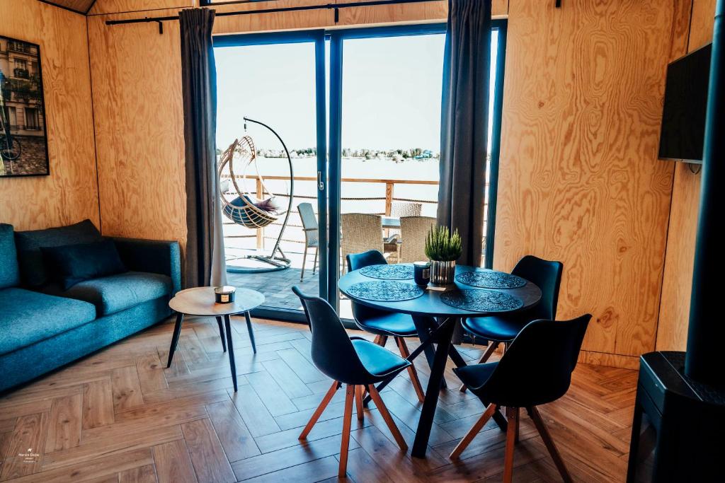 Bright living area with round dining table, sofa and hanging wicker chair opening to balcony.