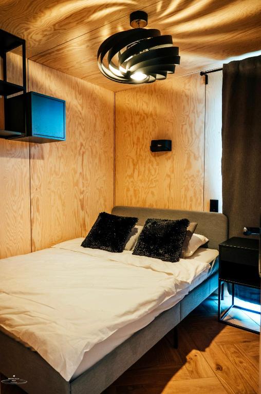 Cozy wooden-paneled bedroom with double bed, black velvet pillows and sculptural ceiling light.