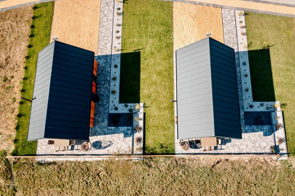 Aerial view of two identical wood cabins with patios, outdoor furniture, and manicured lawns.
