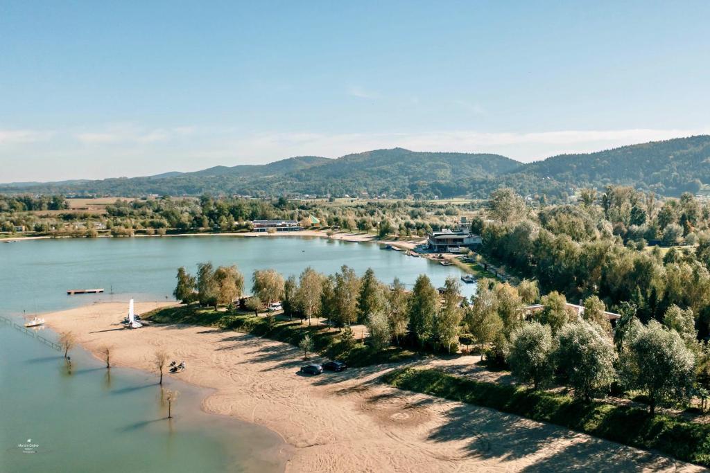 Aerial view of tranquil lake shoreline with sandy beaches, trees, and distant rolling hills.
