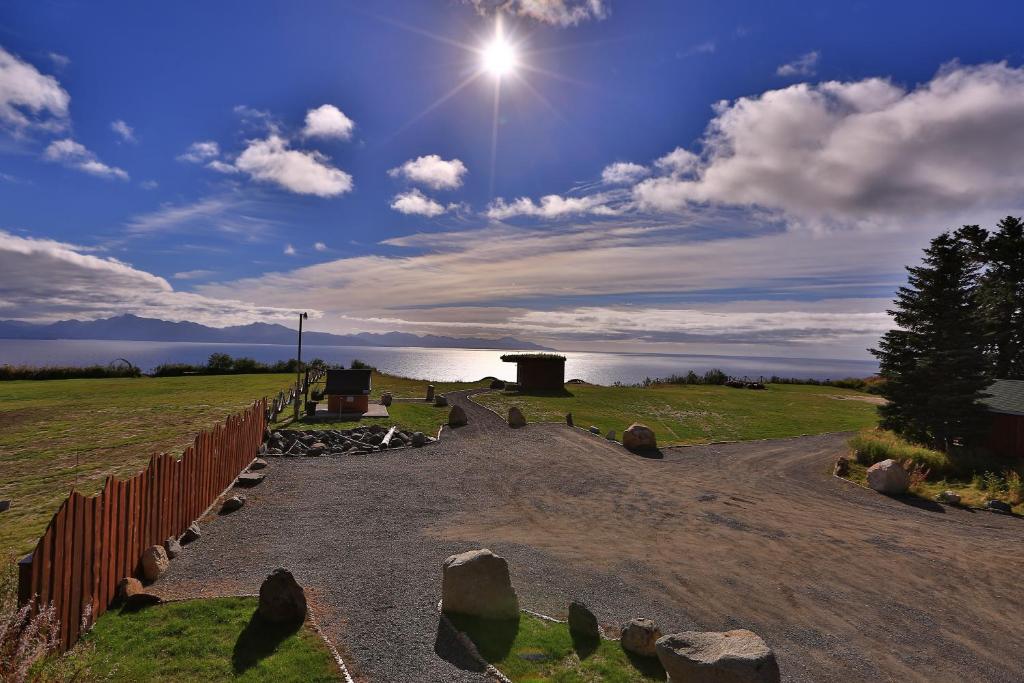 een onverharde weg met een hek en de zon in de lucht bij Kenai Peninsula Suites in Homer