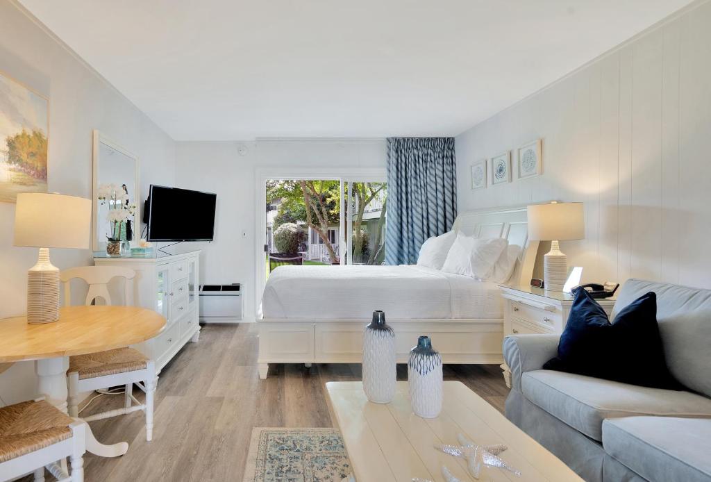 a large white bedroom with a bed and a couch at East Hampton House Resort in East Hampton