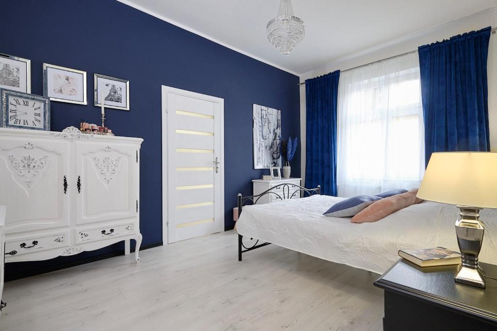 1 dormitorio con cama y pared azul en Art Apartment Szczawno Zdrój en Szczawno-Zdrój