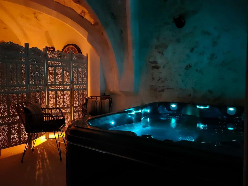 eine Badewanne in einem Zimmer mit einem Tisch und einem Stuhl in der Unterkunft L'envoûtement Provençal, jacuzzi privatif et SPA in Orgon