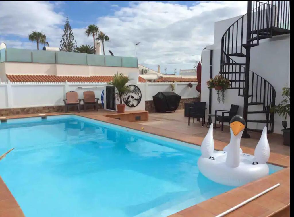 a pool with an inflatable swan in the middle at Villa Bahamas private heated pool close to town. in San Bartolomé de Tirajana
