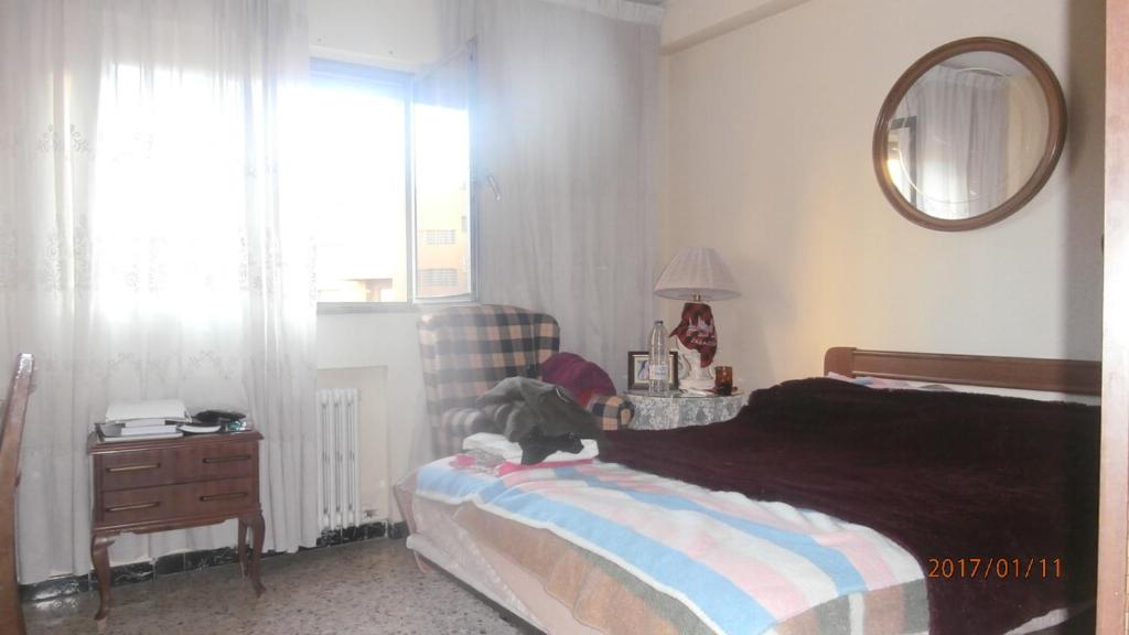 a bedroom with a bed and a mirror and a window at PISO PILARES 6-10 PAX. PARQUE DELICIAS in Zaragoza