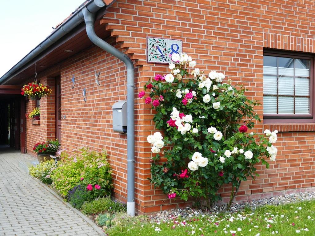 a flower bush on the side of a brick building at Cozy Apartment located in Rovershagen with Garden in Rövershagen