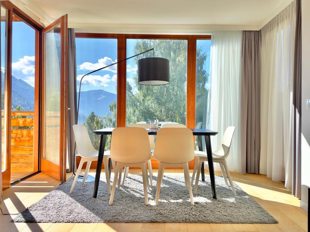 comedor con mesa y sillas y ventana grande en Sunshine @ Rosie Design Chalet en Bad Kleinkirchheim