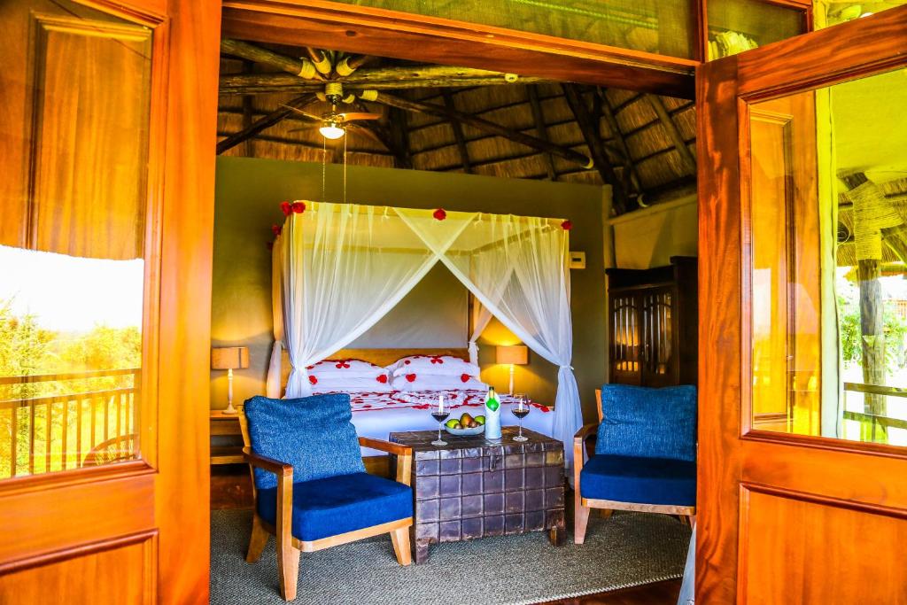una camera con un letto e due sedie blu di Kigambira Safari Lodge a Bakijurura