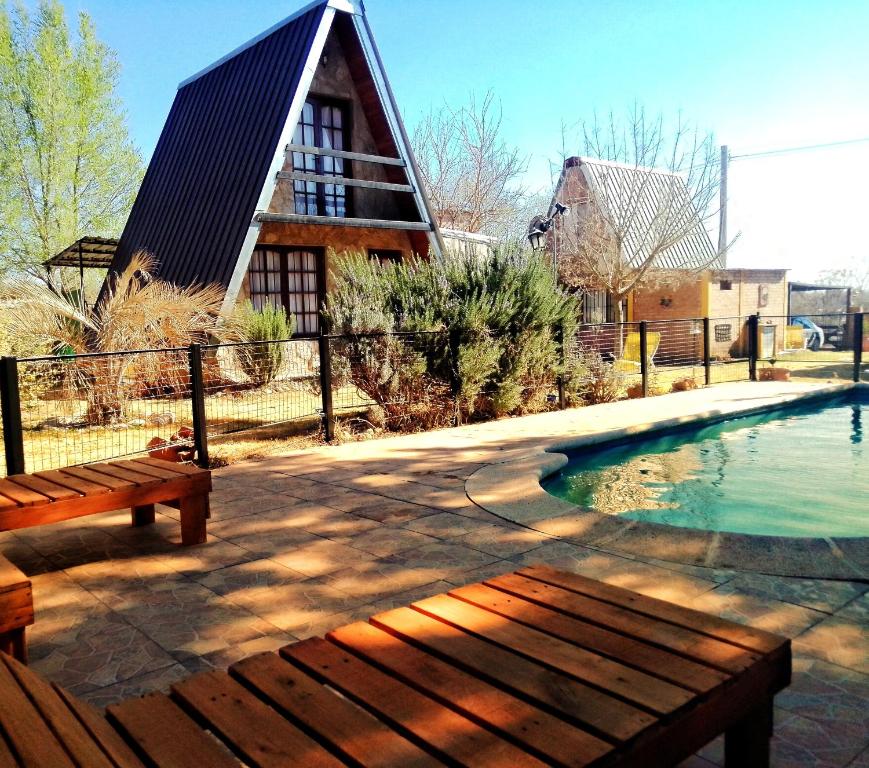 einen Pool mit einer Bank und einem Haus in der Unterkunft Cabañas Alpinas Terra Natura in Bialet Massé