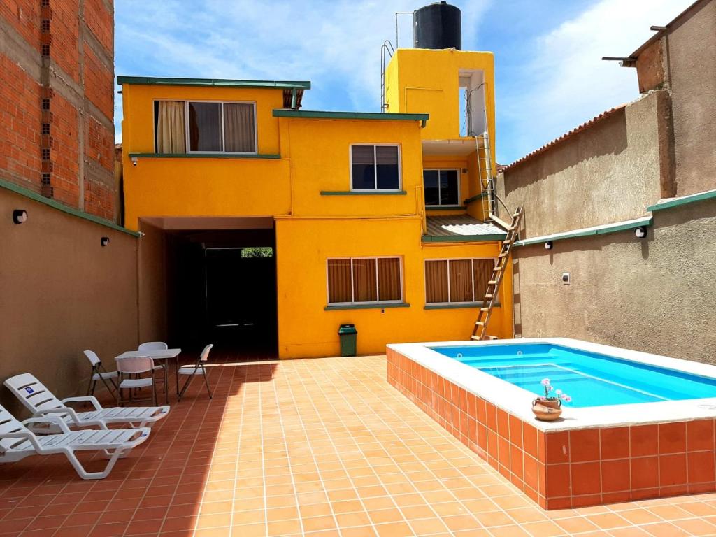 a yellow building with a swimming pool on a patio at Refugio del Turista in Tupiza