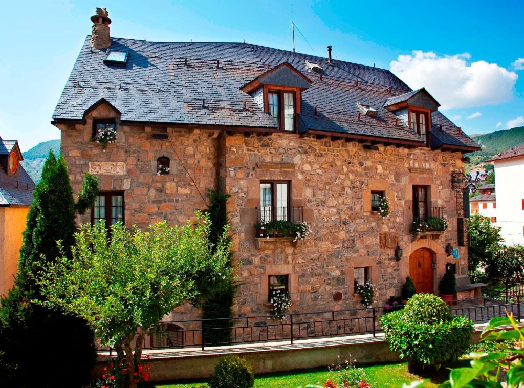 a large stone house with a roof at Hotel Almud in Sallent de Gállego