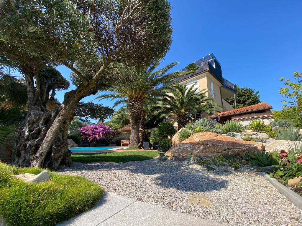 ein Garten mit Palmen und ein Haus in der Unterkunft Apartments Villa BEAUTY PORTOROŽ in Portorož