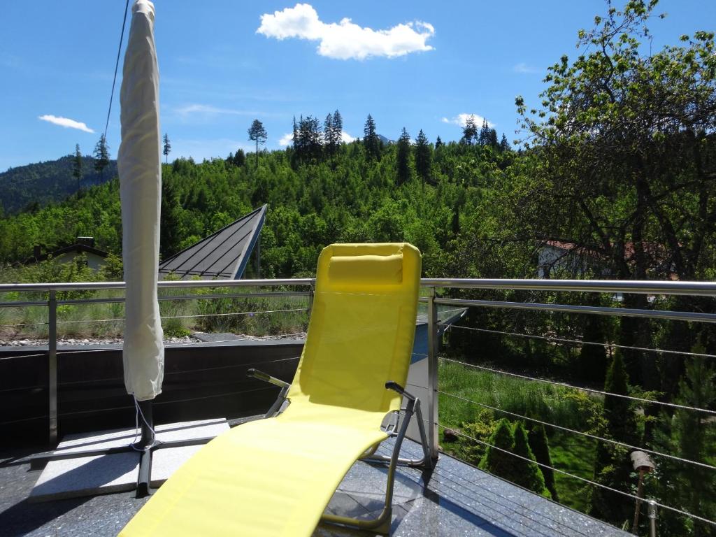 a yellow chair on a balcony with a view of trees at Alpin-Check-in in Reutte