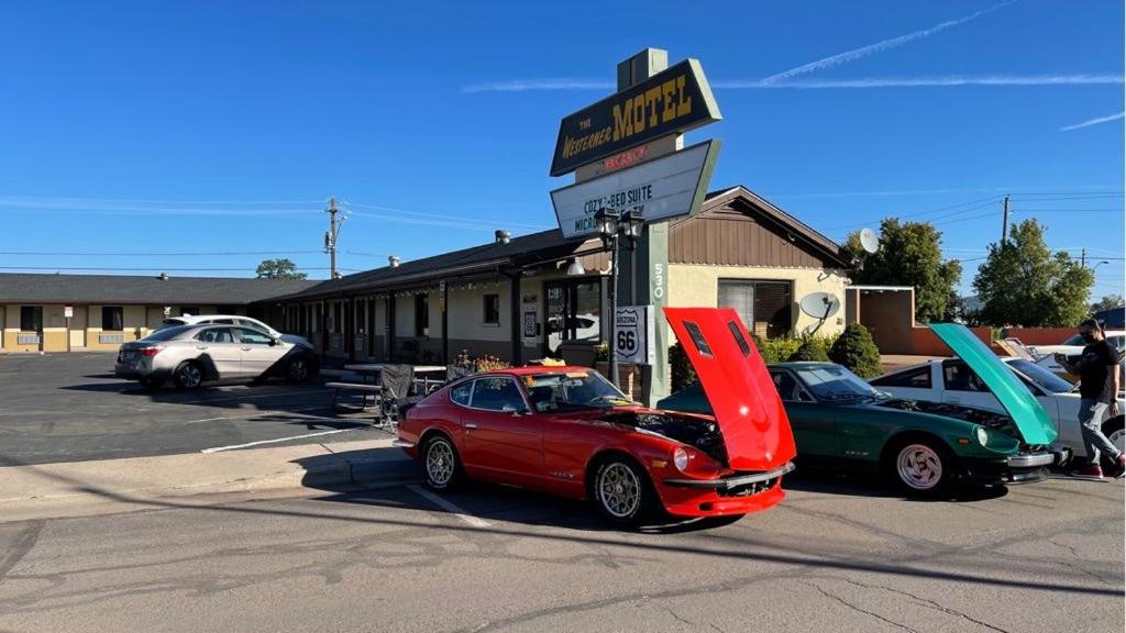 Dos autos están estacionados frente a una gasolinera. en Westerner Motel, en Williams