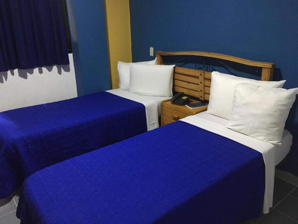 two beds in a hotel room with blue walls at Hotel Renovación in Caracas