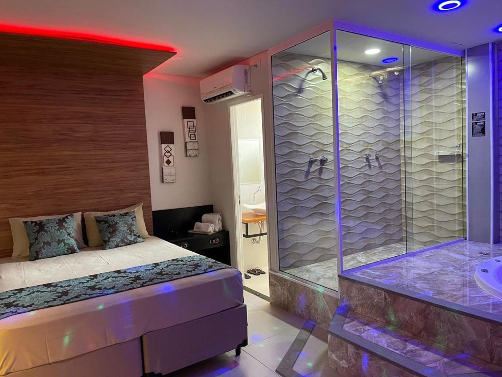 Green It Motel & Hotel في براغانكا باوليستا: غرفة نوم مع دش وسرير وحوض استحمام