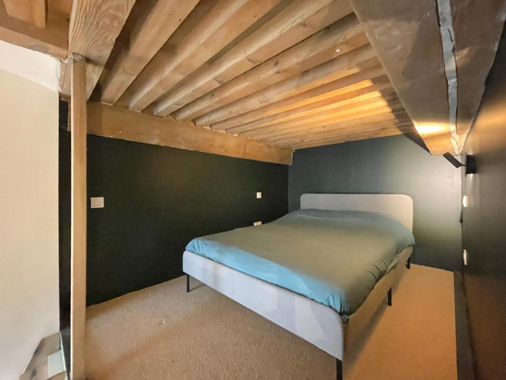 a bed in a room with a wooden ceiling at Le soyeux in Lyon