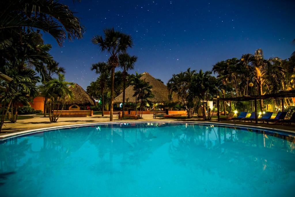 una piscina azul por la noche con montañas en el fondo en Hotel Soleil Pacifico , en Chulamar