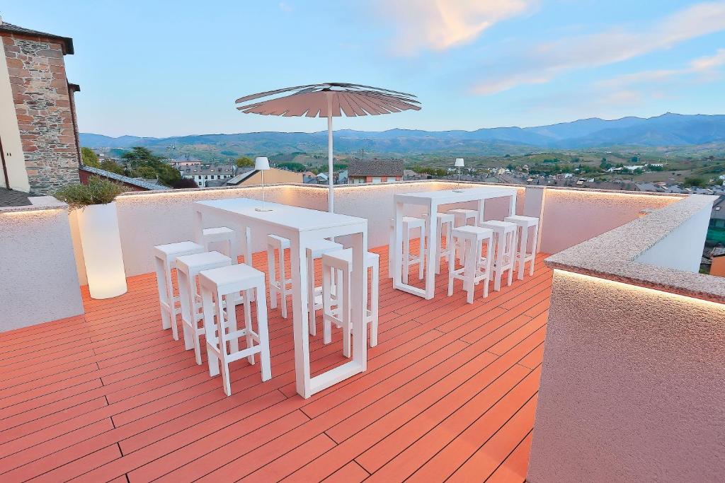 una fila di tavoli e sedie su un balcone con ombrellone di Azotea Suites a Ponferrada