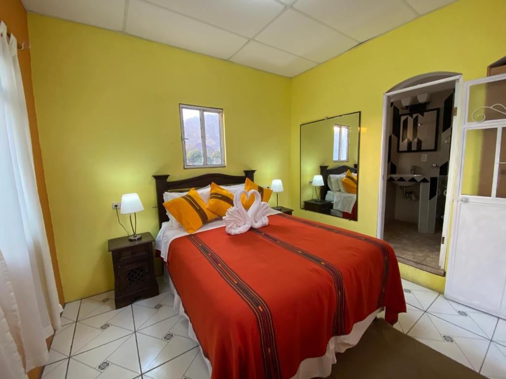 a bedroom with a large bed with a red blanket at Hotel Los Angeles Panajachel in Panajachel