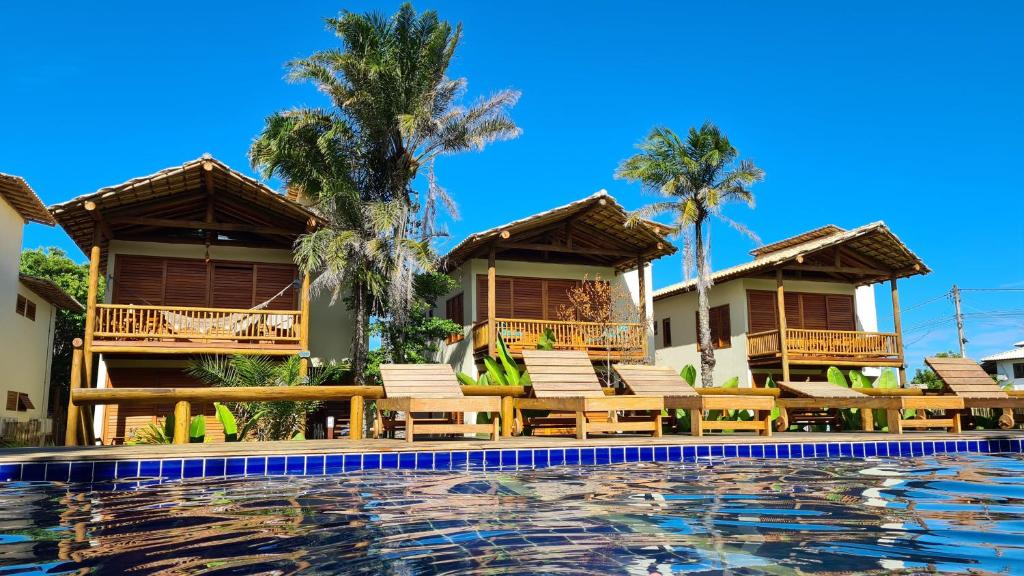 un complejo con piscina, sillas y palmeras en Taipu de Fora - Casa Charme, en Barra Grande