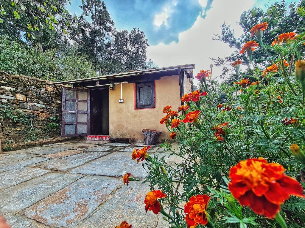 a small house with orange flowers in front of it at Sharda Stay's Binsar Himalayas in Almora