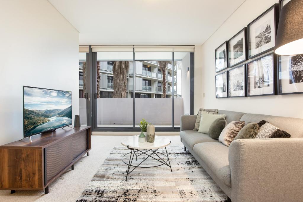 a living room with a couch and a tv at Darling Harbour Apartment near King St Wharf in Sydney