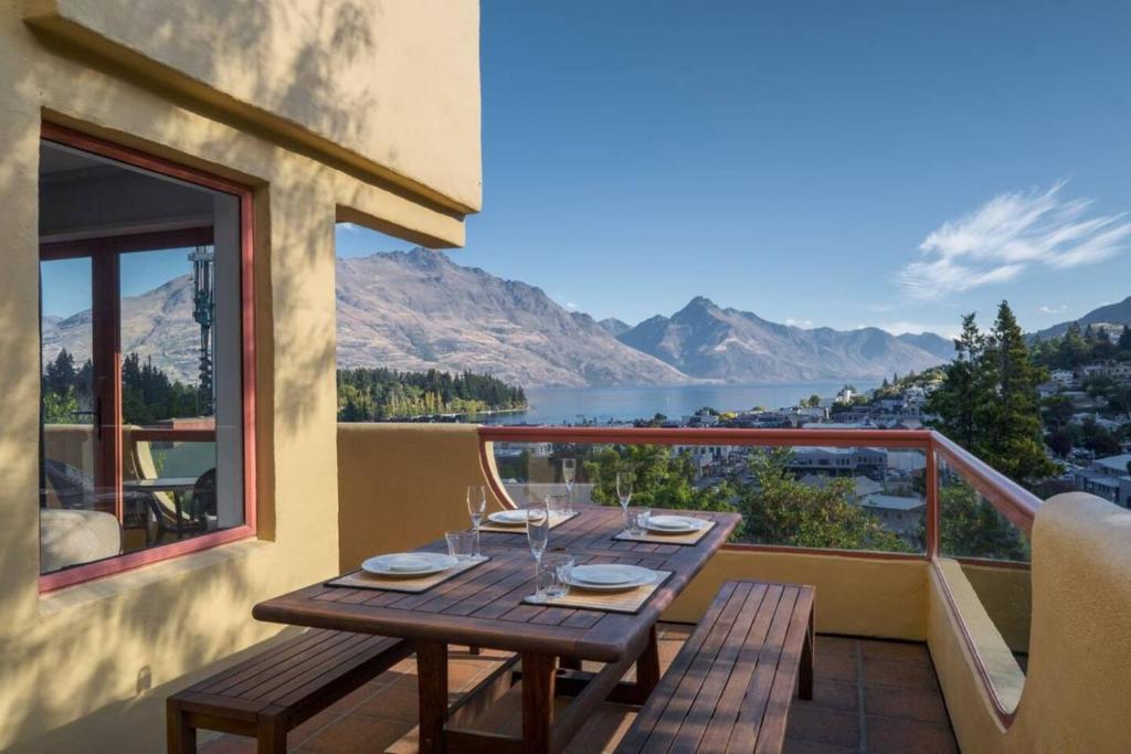 uma mesa de madeira numa varanda com vista para um lago em Magnificent Apartment with Great Views! em Queenstown