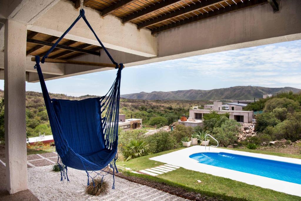 a blue hammock hanging from a house with a swimming pool at Casa de montaña - Carlos Paz in Villa Carlos Paz