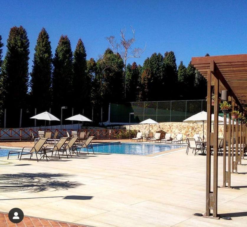 una piscina con sillas y sombrillas junto a en Condomínio Vista Azul hotel en Pedra Azul