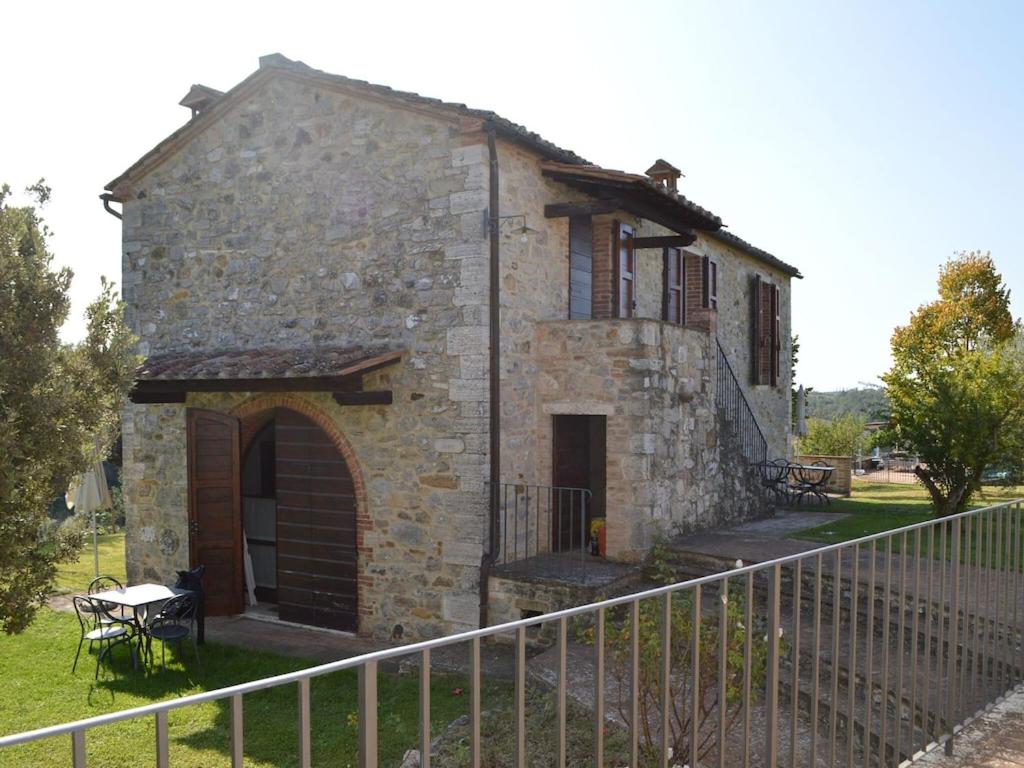 an old stone house with a fence in front of it at Belvilla by OYO Appartamento Dante in Serre di Rapolano