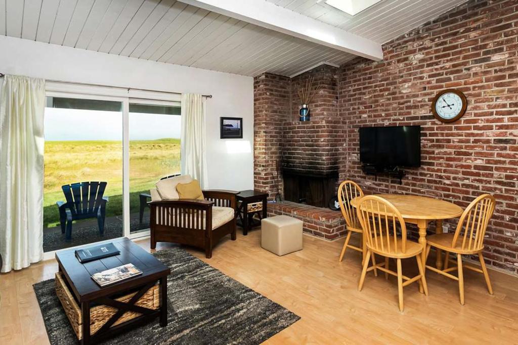 a living room with a brick wall and a table and chairs at Cottage by the Sea in Gearhart