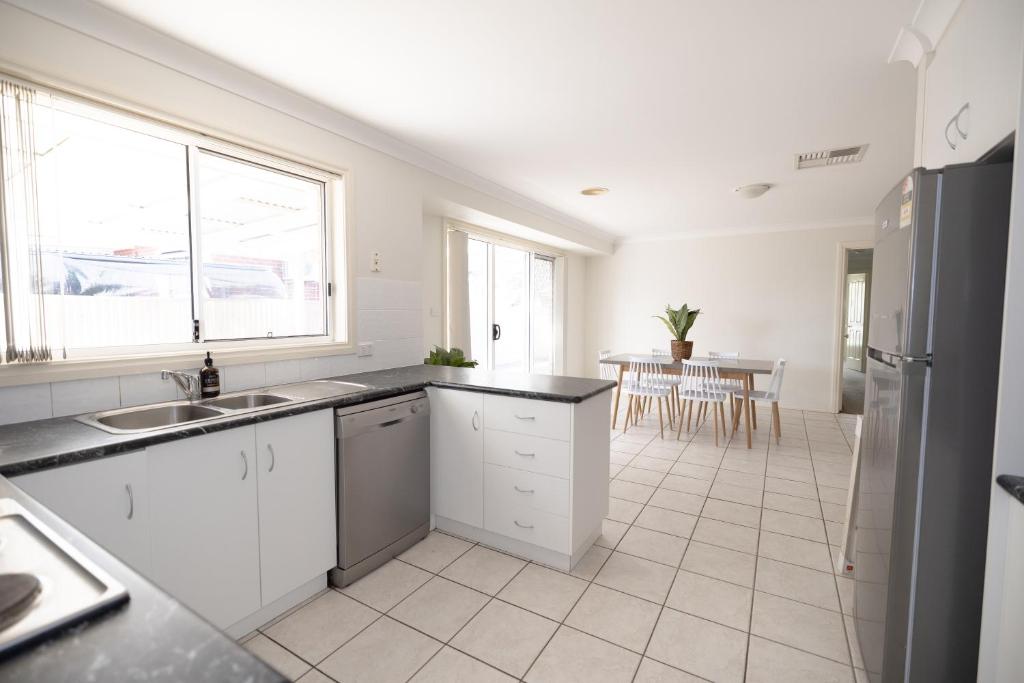 a kitchen with white cabinets and a large window at Wagga Apartments #8 in Wagga Wagga