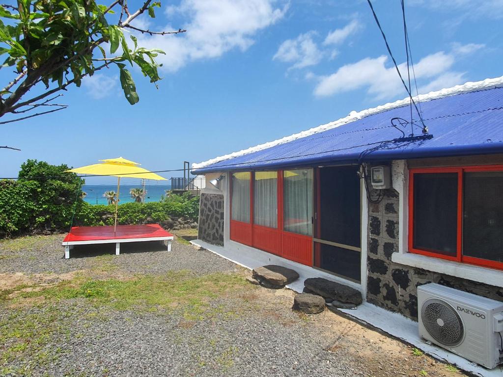 ein kleines Haus mit einem Tisch und einem Sonnenschirm in der Unterkunft Hamdeok Saeya Saeya Entire House in Jeju-do