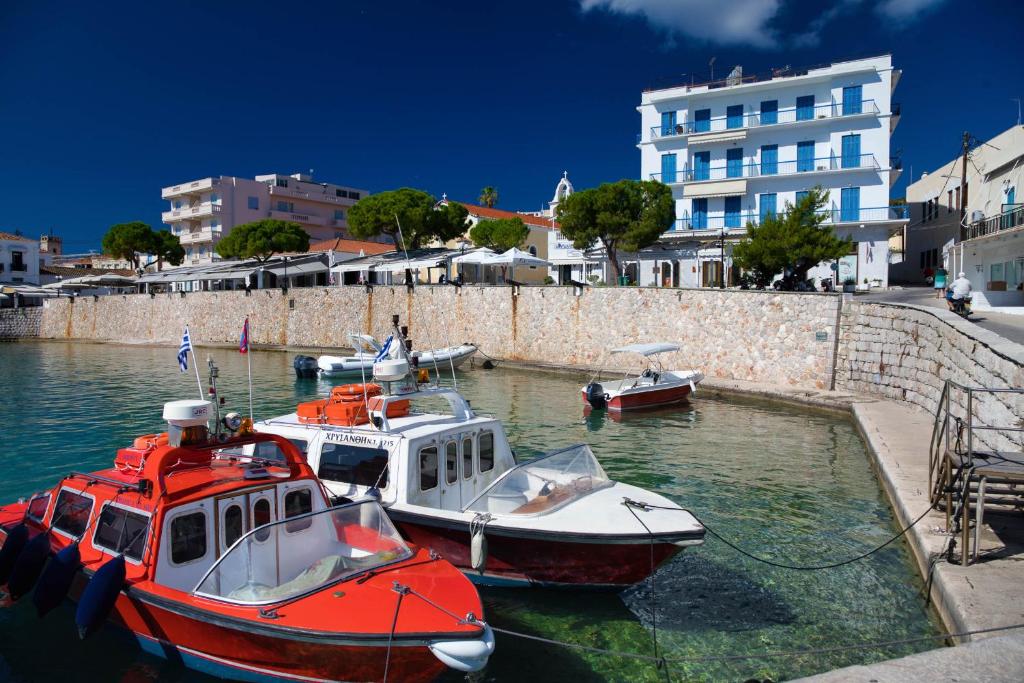 three boats are docked in the water near a building at Argonaftis Spetses in Spetses
