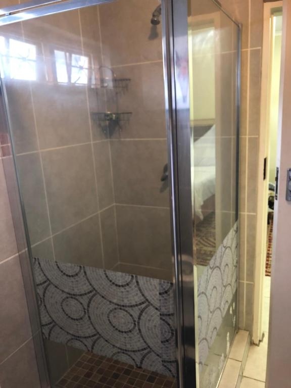 a shower with a glass door in a bathroom at Lovely self catering first floor apartment in Roodepoort