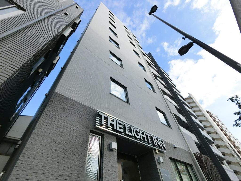 un edificio alto con un cartel en el costado en The Light Inn Tokyo, en Tokio