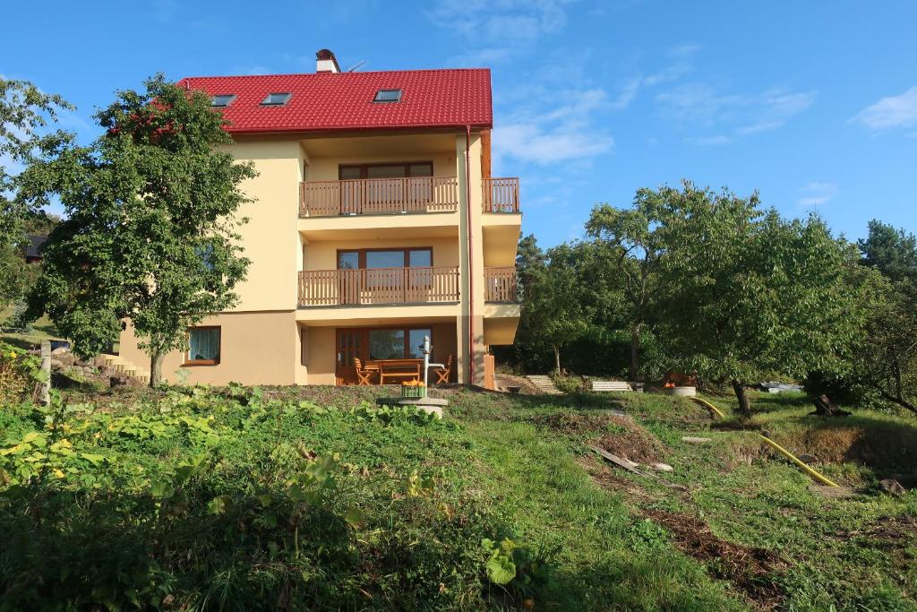 a house with a red roof on a hill at Apartmány U Zvoničky in Prachov
