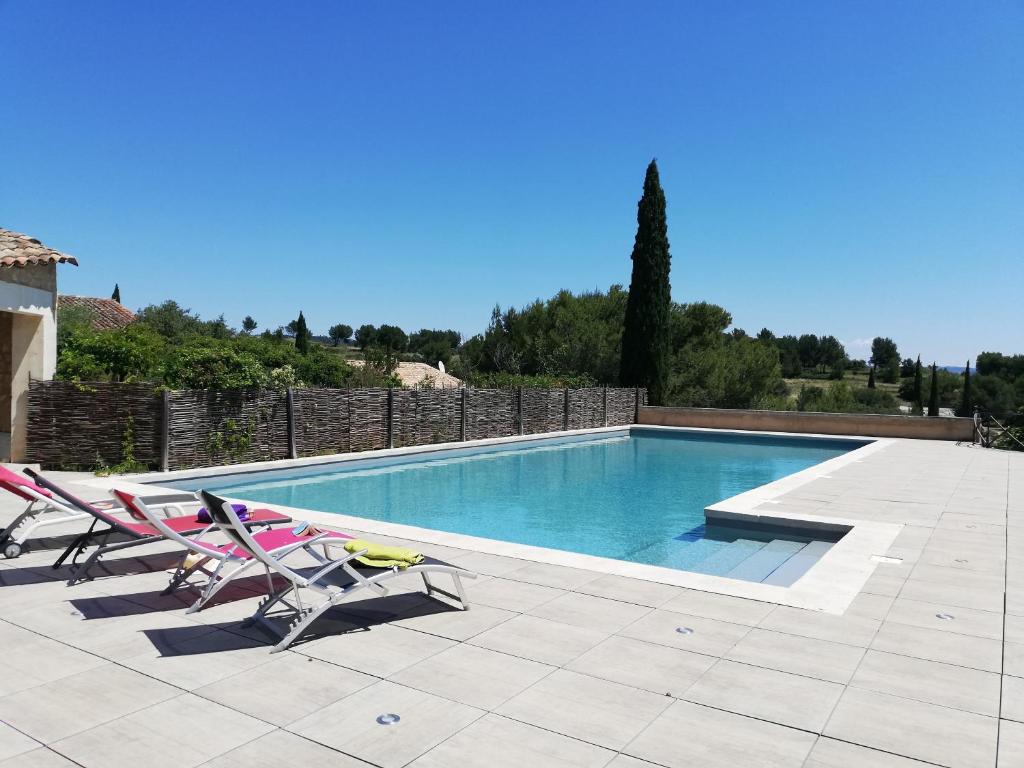 uma piscina com duas espreguiçadeiras e uma piscina em Les Garrigues de la Vallée des Baux em Paradou