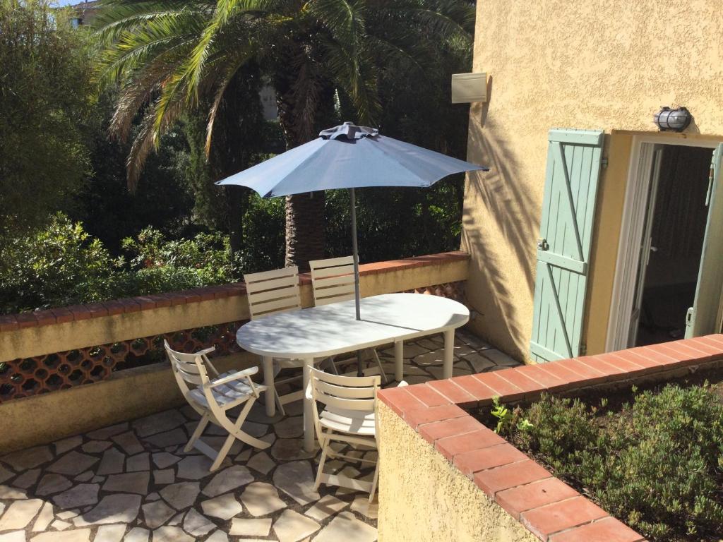 une table et des chaises avec un parasol sur une terrasse dans l'établissement Villa Macoran 2 étoiles, à Saint-Aygulf