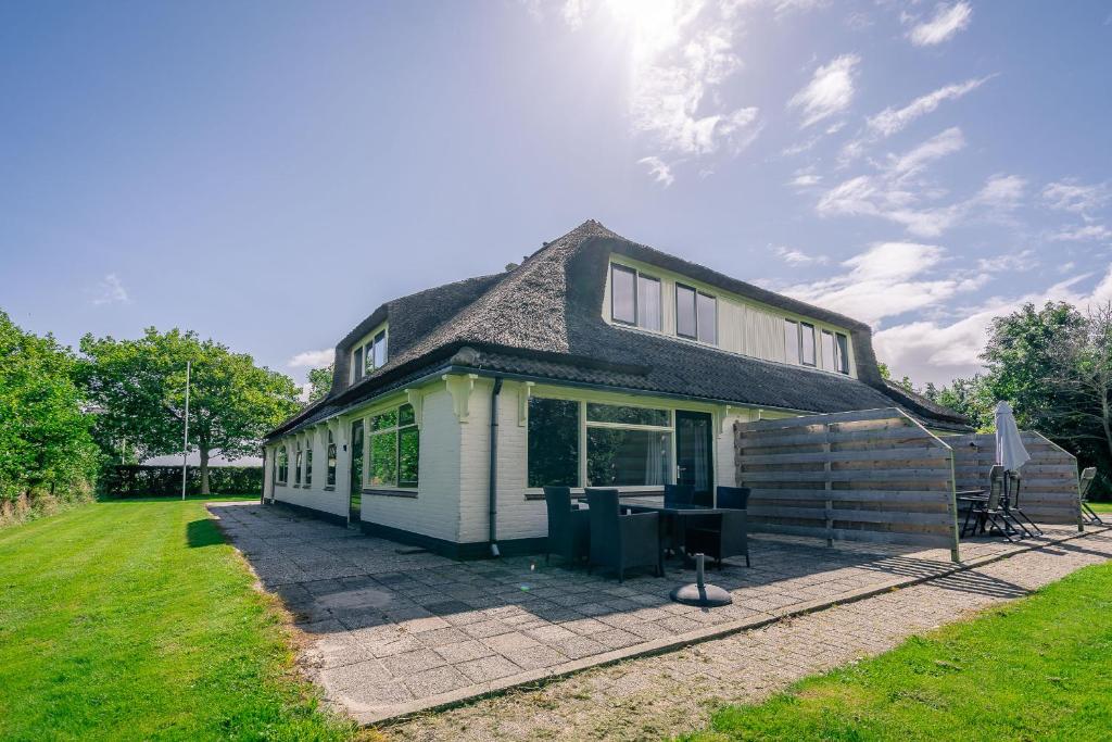 una casa blanca con techo de gambrel en Nieuwlanderweg 61, en De Waal