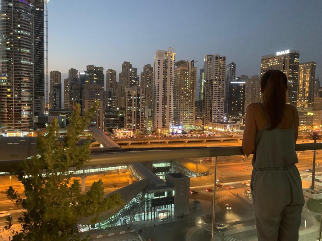 a woman standing on a balcony looking at a city skyline at Luxury apartment on the metro facing Dubai Marina in Dubai