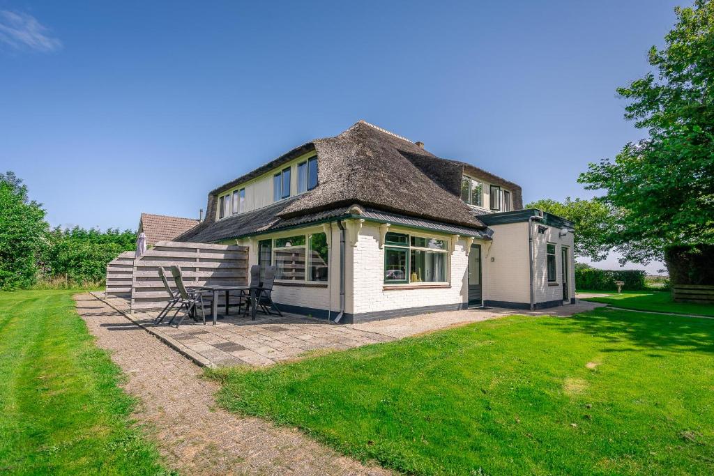 a house with a thatched roof and a patio at Nieuwlanderweg 65 in De Waal
