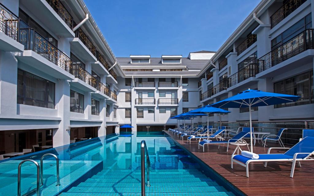 una piscina con sillas y sombrillas en un edificio en Royale Chulan Penang, en George Town