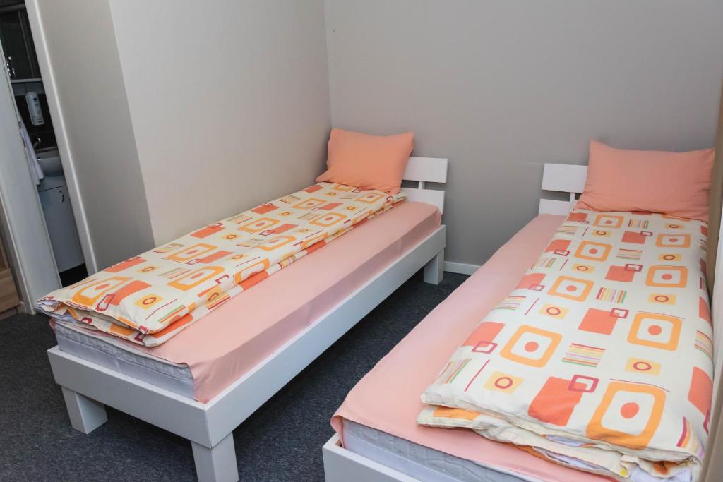 two beds in a room with pink and orange pillows at Anin Dvor Šekovići in Šekovići